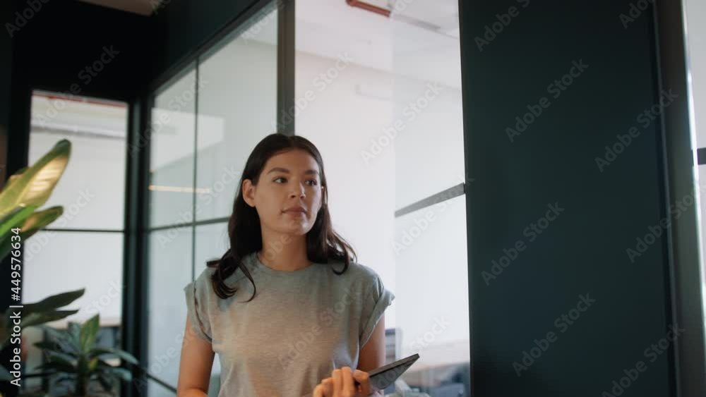 Young businesswoman leaving office with laptop and walking along corridor of modern open plan building shot in slow motion Young businesswoman leaving office with laptop and walking along corridor of modern open plan building shot in slow motion