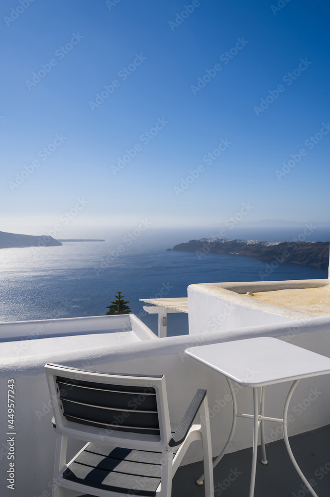Chair and table on terrace of luxury hotel. View of caldera. Santorini island, Greece. Volcano. Aegean sea. White architecture.