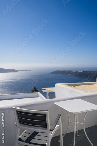 Chair and table on terrace of luxury hotel. View of caldera. Santorini island, Greece. Volcano. Aegean sea. White architecture. © Anastasia