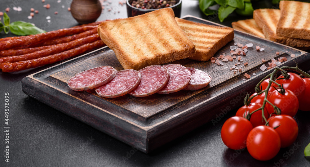 Spanish dried sausage salami on a dark concrete background