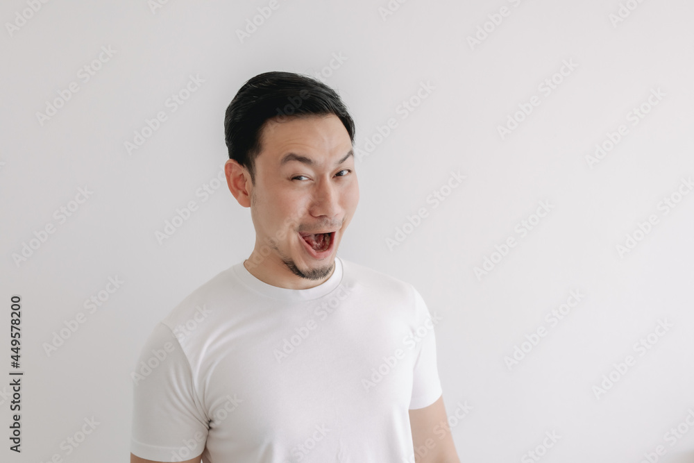 Funny grin smile face of Asian man in white t-shirt isolated on white wall. Funny grin smile face of Asian man in white t-shirt isolated on white wall.