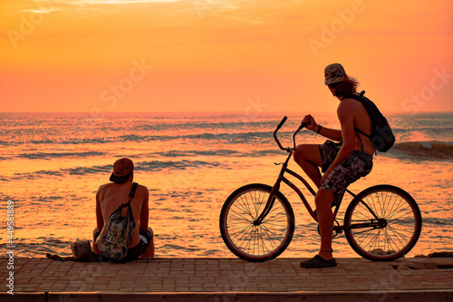 Two friends watching the sunset after a day of surfing