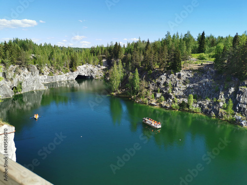 View from the observation deck of the turquoise water of the Marble Canyon in the Ruskeala Mountain Park with the reflection of the sky and trees on a sunny summer day.