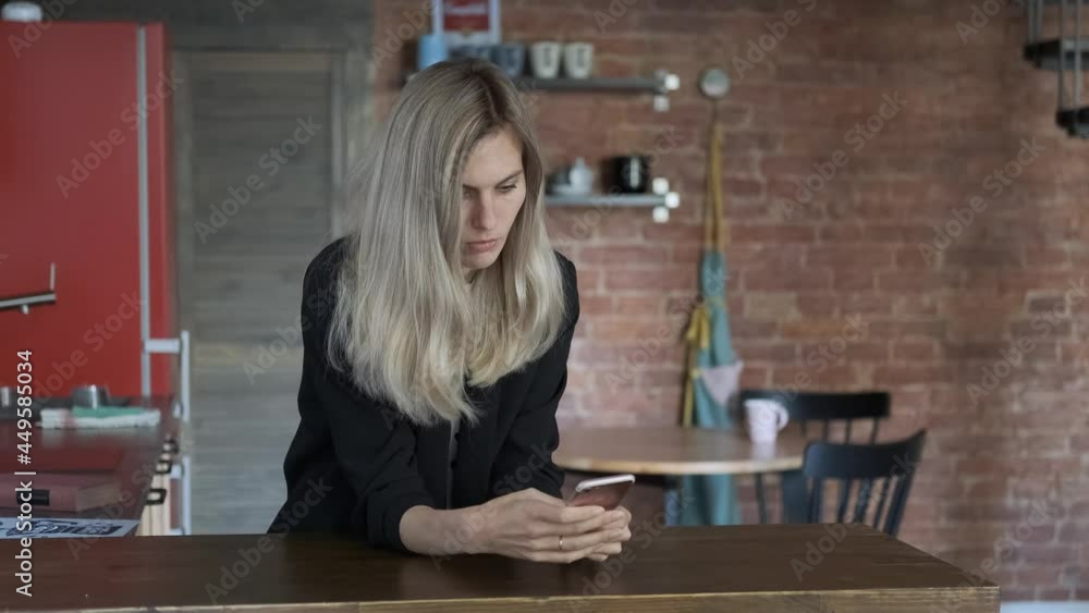 stylish woman uses smartphone while sitting in the kitchen stylish woman uses smartphone while sitting in the kitchen