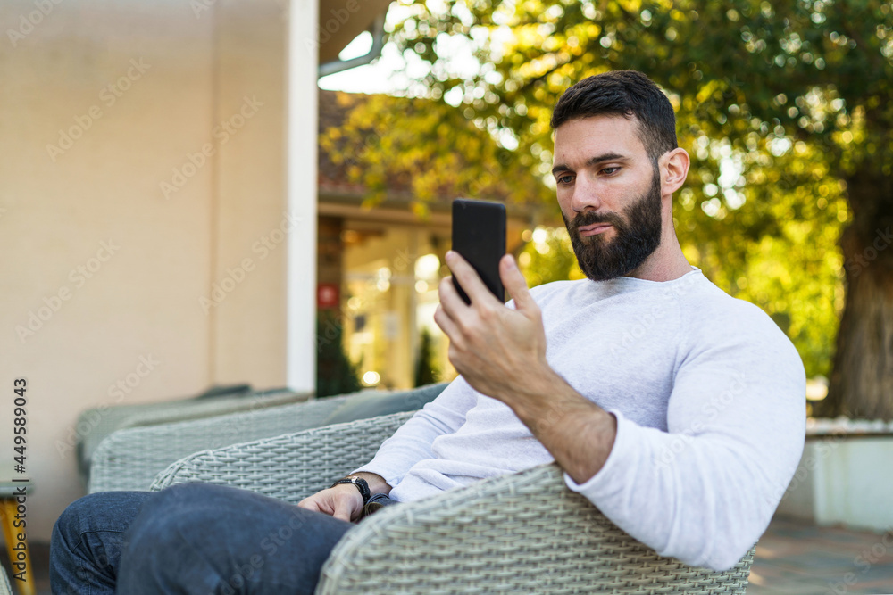 Side view portrait of adult modern caucasian man with beard sitting outdoor serious using mobile phone for video call at cafe in autumn day - leisure concept copy space Side view portrait of adult modern caucasian man with beard sitting outdoor serious using mobile phone for video call at cafe in autumn day - leisure concept copy space