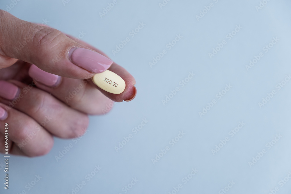 Hand holding a yellow pill. Pharmacy and medicine concept. Hand holding a yellow pill. Pharmacy and medicine concept.