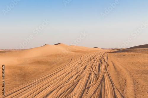 Lonely desert road driving lanes amid golden sand dunes. Climate change heat and dryness up to horizon produces erosion and desertification. Landscape showing waste adventure travel tourism