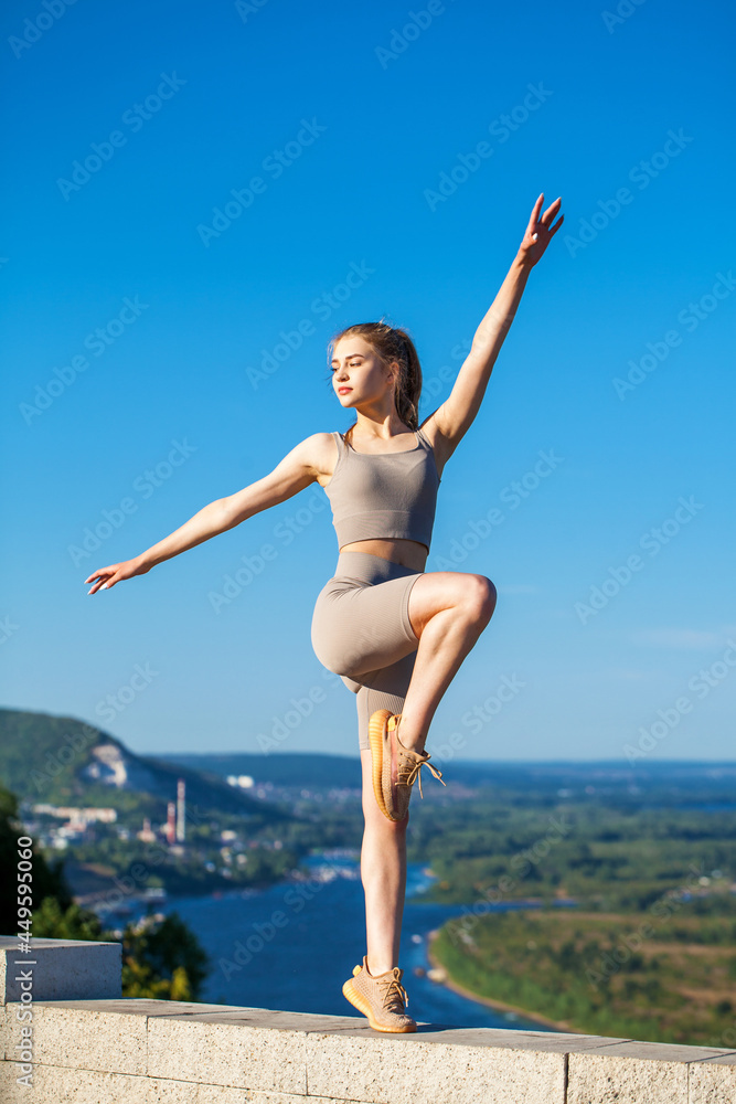 Young beautiful blonde woman in sports uniform is engaged in fitness outdoors