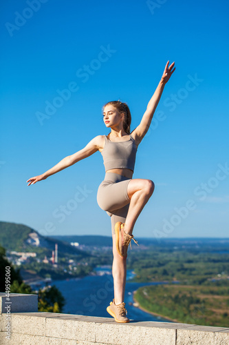 Young beautiful blonde woman in sports uniform is engaged in fitness outdoors