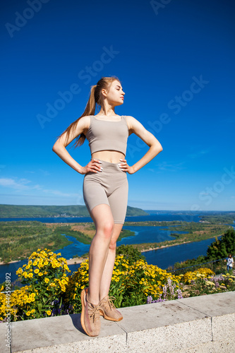 Young beautiful blonde woman in sports uniform is engaged in fitness outdoors