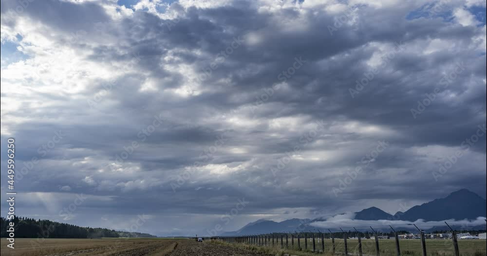 Time lapse of clouds moving over Ljubljana airport, Slovenia. View of aerodrome fence and farming field. Mountains in the distance. Static shot Time lapse of clouds moving over Ljubljana airport, Slovenia. View of aerodrome fence and farming field. Mountains in the distance. Static shot