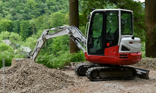 Mini excavator on the mountain surrounded by trees