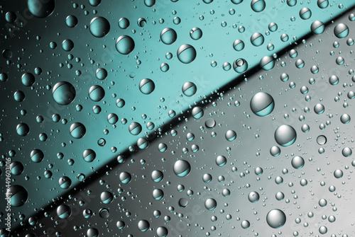 Abstract split background with water drops on the glass. Blue and silver. Close up.