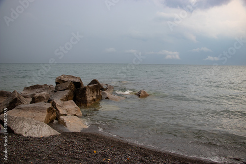 Coastal beach with granite stones embeded in the shoreline of Lake Ontario photo