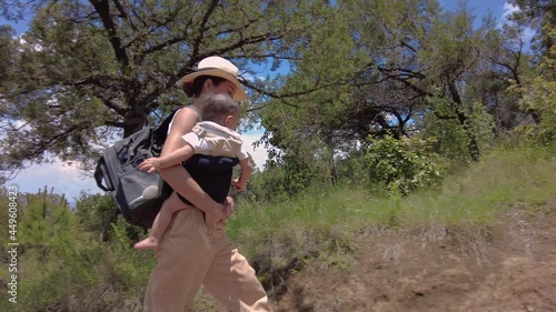Attractive young latin girl woman mom with her baby boy child son toddler in her arms at the woods in a sunny day with dogs pets.  Family trip concept