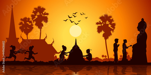 country life of Asia children play water and build sand pagoda while couple pour water to Buddha sculpture on sunrise time,silhouette style