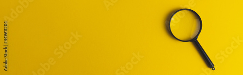 Black magnifying glass on a yellow background. Search concept. Baner format. Copy space text.