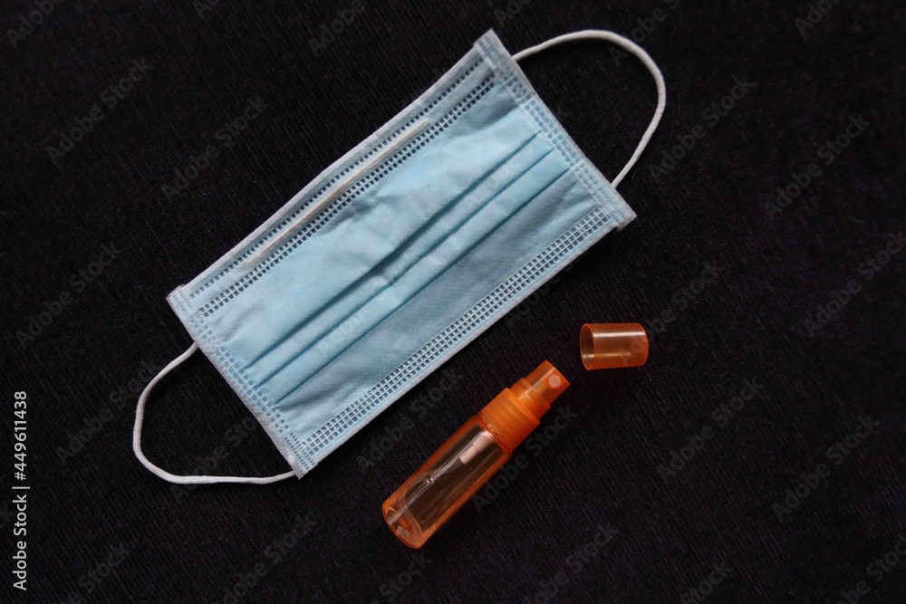 blue medical mask and hand sanitizer bottle on black background blue medical mask and hand sanitizer bottle on black background