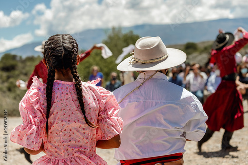Young couple in traditional costumes watch a typical dance performance at the festival welcoming new tourists in Cachi, Salta, Argentina photo