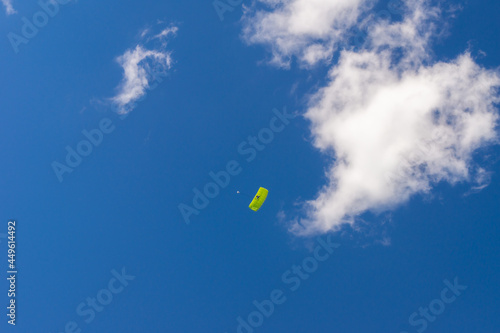 a parachutist under a green canopy of a parachute flies over the audience