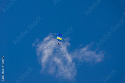 blue paraglider soars against a background of blue sky and clouds