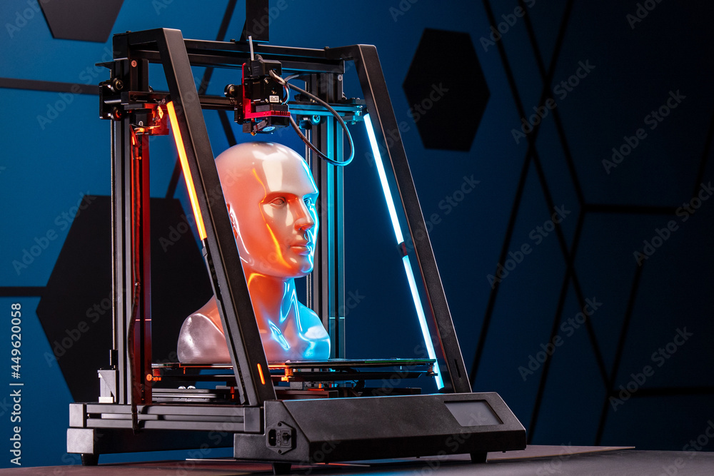 3D printer at work. 3d printer prints head, advertising photo blue and orange light. Copy space