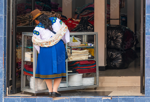 Ecuadorian indigenous Otavalo woman in traditional clothing shopping in textile fabric shop, Otavalo, Ecuador.