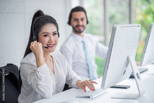 young asian woman working receiving call wear headphone consulting or solving problems for customers,Employees wearing headphones doing telemarketing,man blurr background