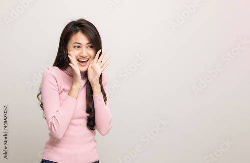 Excited asian woman shout out loud wow with hands on isolated background. Happy shocked face female wow promotion advertising concept. Joyful teenage girl in pink shirt standing in white room.