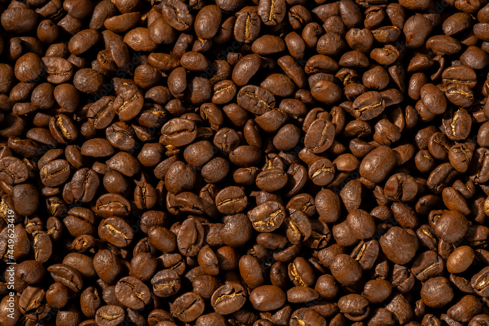 Obraz premium Roasted coffee beans closeup Background, Coffee grains scattered on the table, working hours coffee, hot drinks.