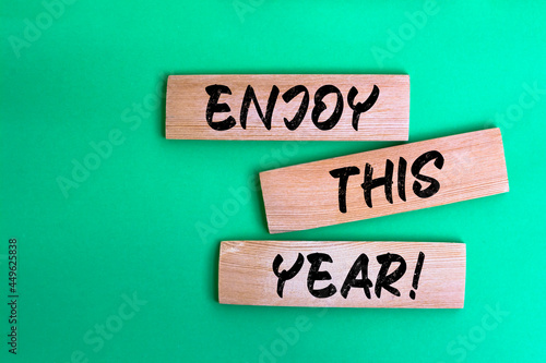 The words Enjoy this year write on wooden block.