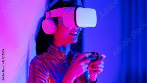 Young asian woman is using virtual reality headset. Neon light studio portrait. Concept of virtual reality, simulation, gaming and future technology.Asian woman play game in bedroom. © anon