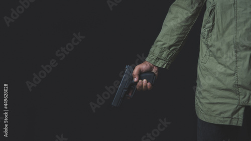 Man holding a gun in his hand with a black background.