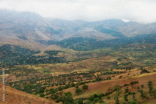 Moroccan landscape with foggy mountains and fields.