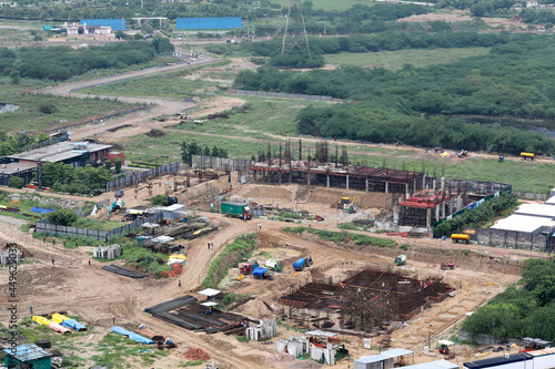 Aerial drone image (top view) of a construction site. Heavy equipment is grading the land, moving and flattening out red clay soil.