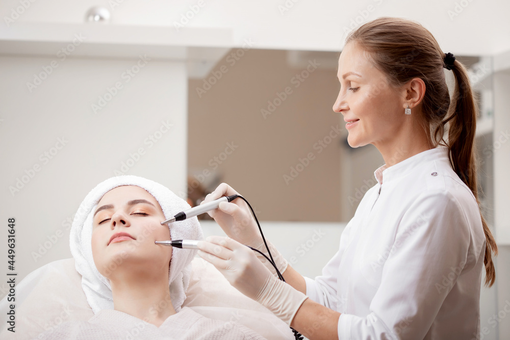 Young woman having stimulation microcurrent procedure for lifting skin face treatment from spa clinic Young woman having stimulation microcurrent procedure for lifting skin face treatment from spa clinic