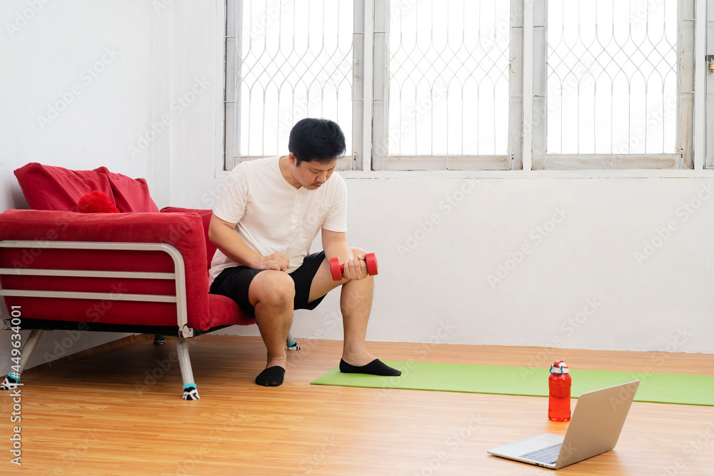 Fototapeta premium Online workout. Young man doing plank exercise with online tutorial at home, Internet fitness class or video course.