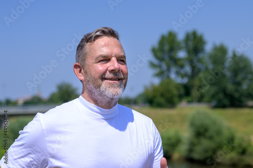 Bearded middle-aged man grinning happily as he jogs outdoors