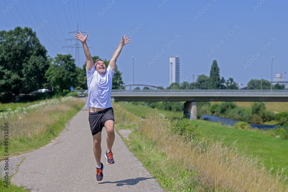Joyful exuberant middle-aged man out jogging along a river