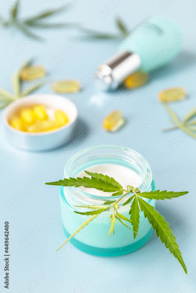 Herbal Alternative Medicine Concept, cosmetics CBD oil. Cannabis leaf skincare cosmetic product. Moisturizing cream, Serum, capsules oil on a pastel blue background. Herbal Alternative Medicine Concept, cosmetics CBD oil. Cannabis leaf skincare cosmetic product. Moisturizing cream, Serum, capsules oil on a pastel blue background.
