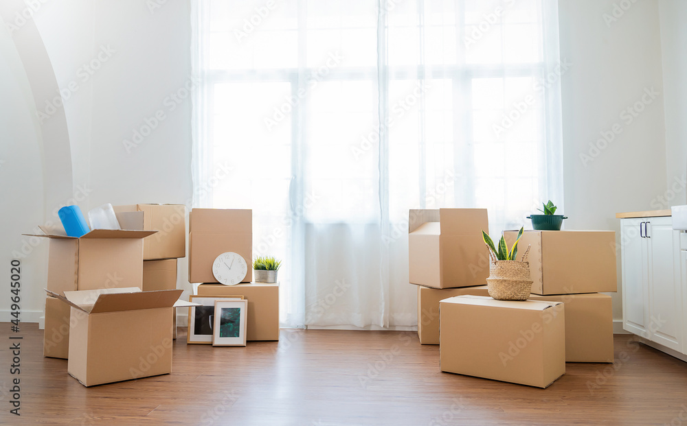 Moving in. Stack of cardboard boxes and household stuff belongings in the white empty apartment room carton with copy space. Lifestyle moving house relocation unpacking background concept banner Moving in. Stack of cardboard boxes and household stuff belongings in the white empty apartment room carton with copy space. Lifestyle moving house relocation unpacking background concept banner