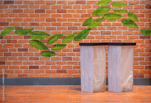 Two transparent trash cans on the orange floor with wave green leaves on the new brick wall background with copy space.