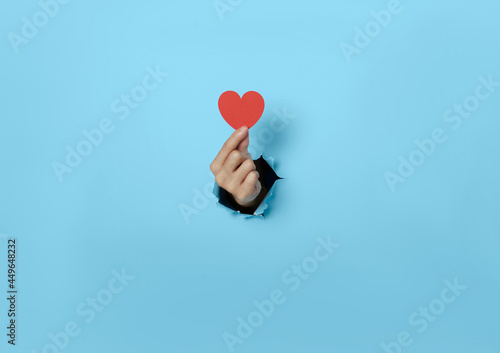 Woman hand holding heart on blue background. photo