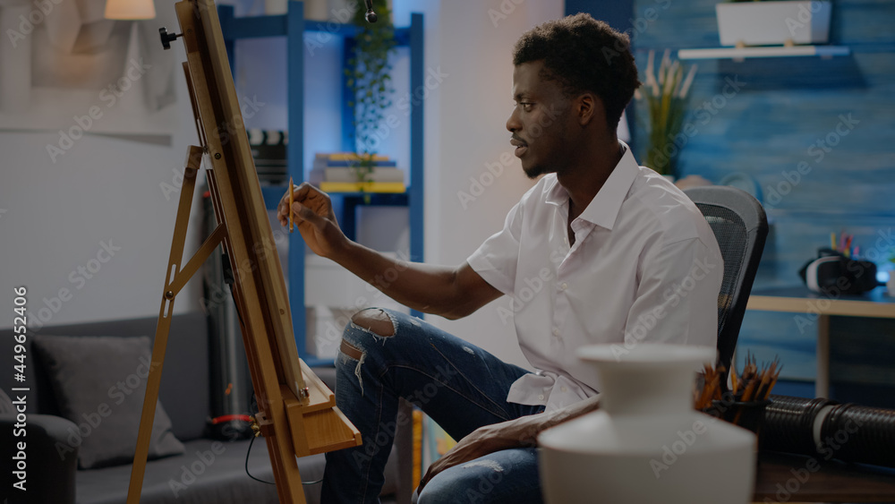 Adult of african american ethnicity drawing vase on canvas using pencil while sitting in art studio at home. Black young person with artistic imagination creating modern masterpiece Adult of african american ethnicity drawing vase on canvas using pencil while sitting in art studio at home. Black young person with artistic imagination creating modern masterpiece