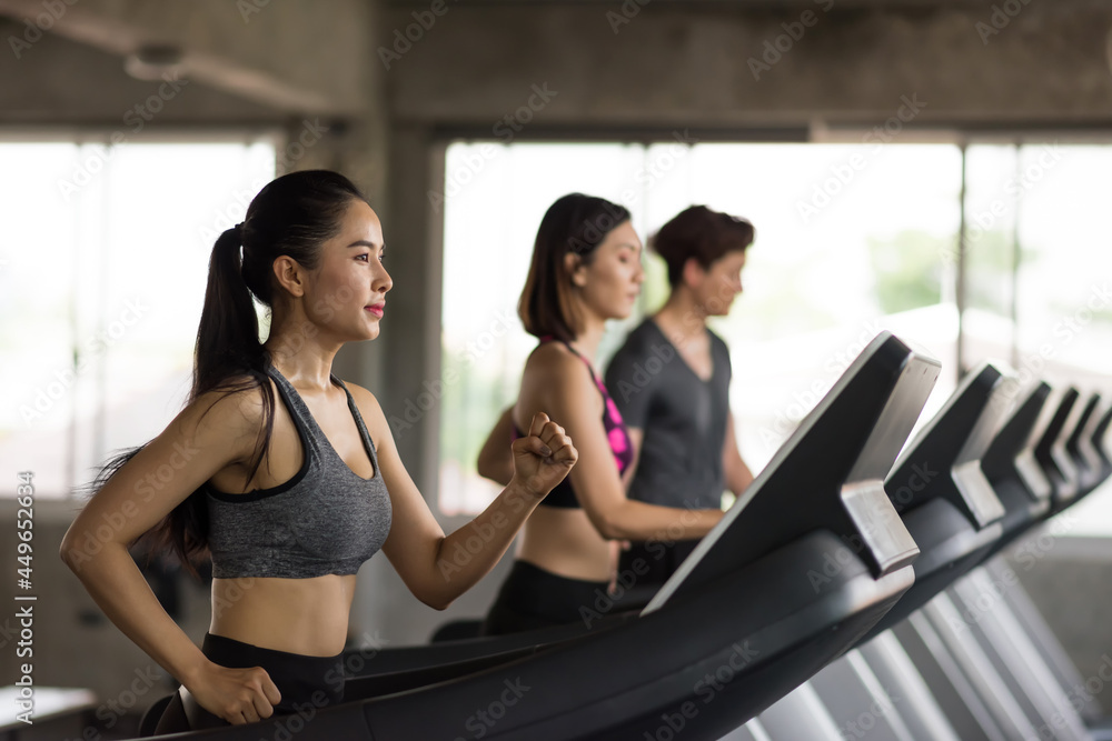Asian friends running exercise on treadmills at gym Asian friends running exercise on treadmills at gym