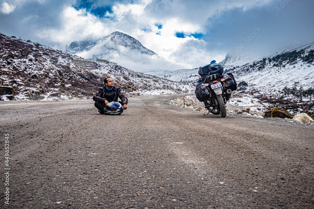 man solo traveler at isolated tarmac road with snow cap mountains in background at morning man solo traveler at isolated tarmac road with snow cap mountains in background at morning