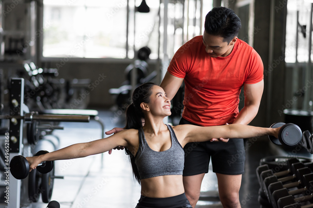 man set postion of dumbbell to woman in gym man set postion of dumbbell to woman in gym