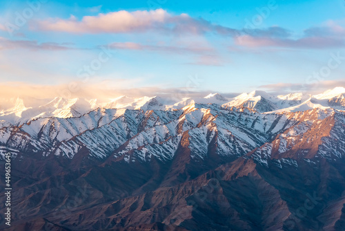 Beautiful panoramic view of a mountainside lit at the sunset period and also including of a snow found high up in the mountain peaks.
