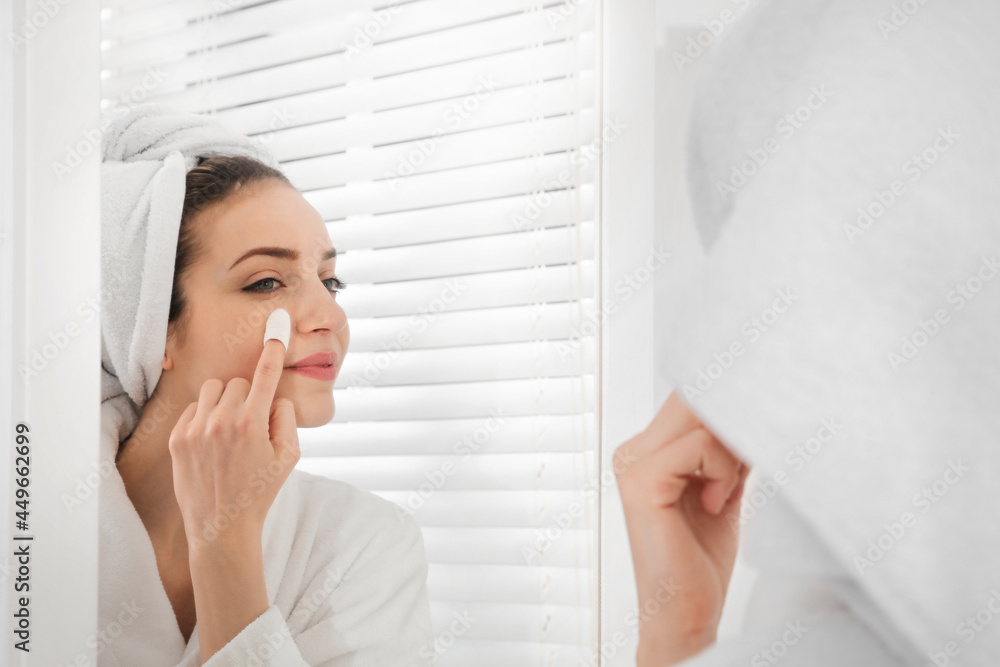 Woman using silkworm cocoon in skin care routine near mirror at home Woman using silkworm cocoon in skin care routine near mirror at home