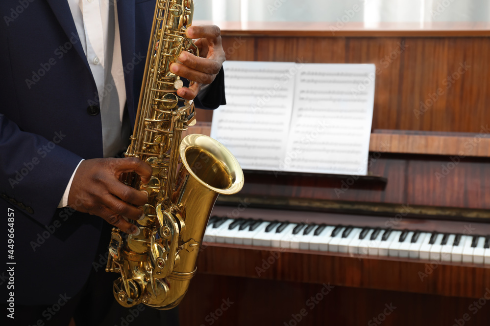 Naklejka premium African-American man playing saxophone indoors, closeup with space for text. Talented musician